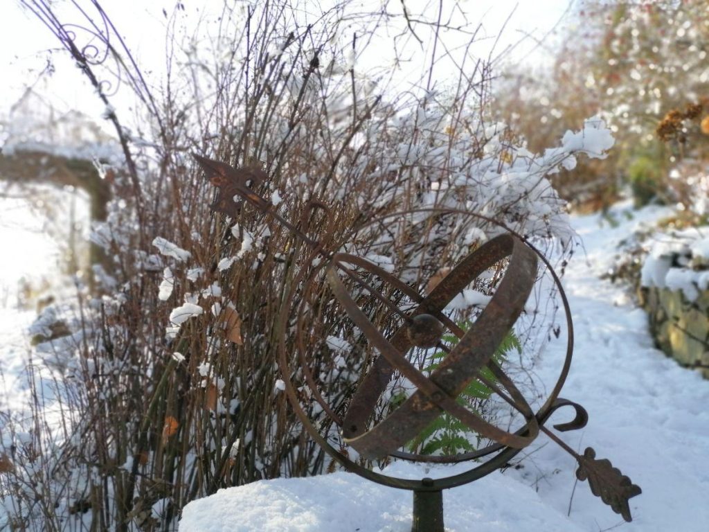 Sonnenuhr vor winterlichen Garten